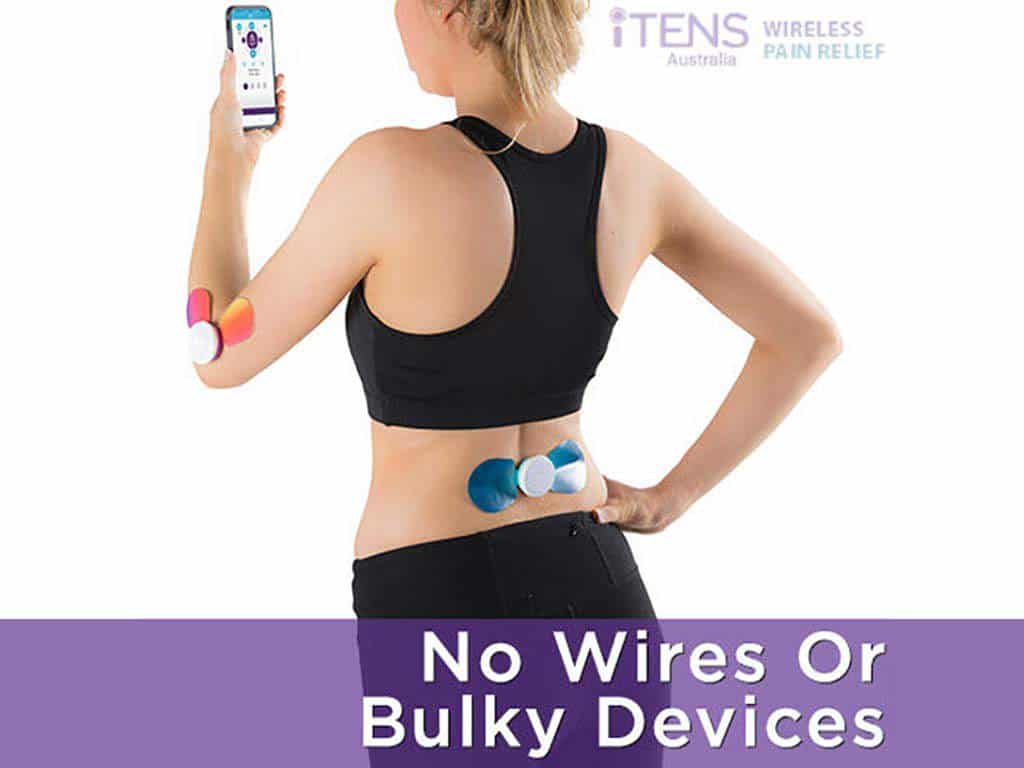 Woman using a wireless TENS machine on the back while holding a smartphone