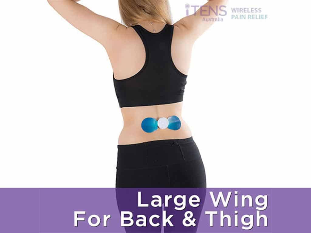 A standing woman using TENS on her lower back