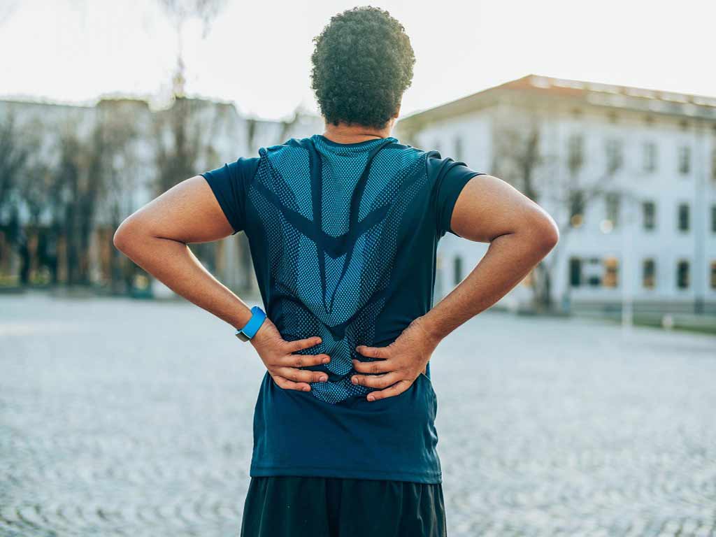 A man holding taking a break from exercising due to back pain