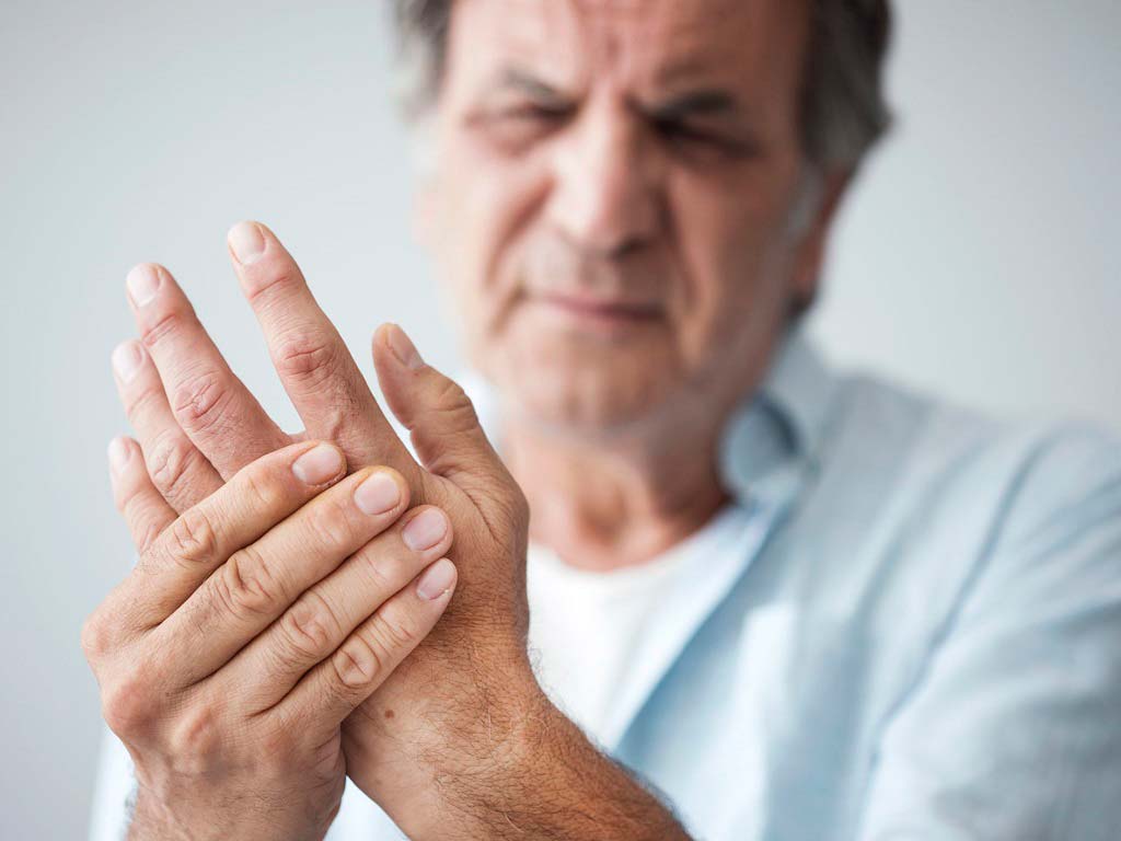 An elderly man frowning because of his hand pain