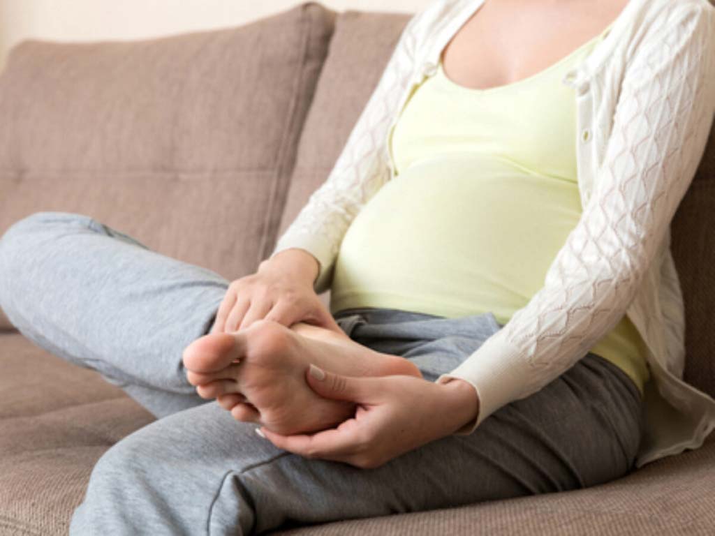 Pregnant woman massaging feet as treatment
