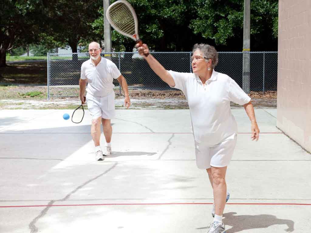 Two elderly individuals playing a game of tennis.