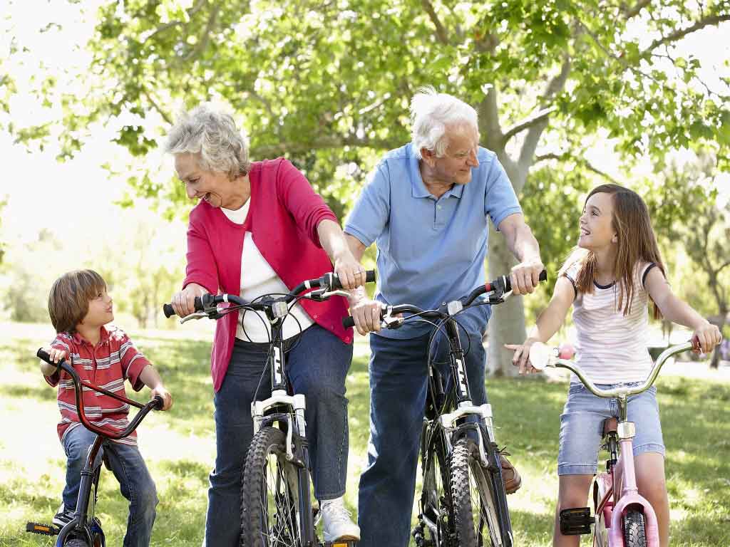 Elderly man and woman riding a bicycle with two kids