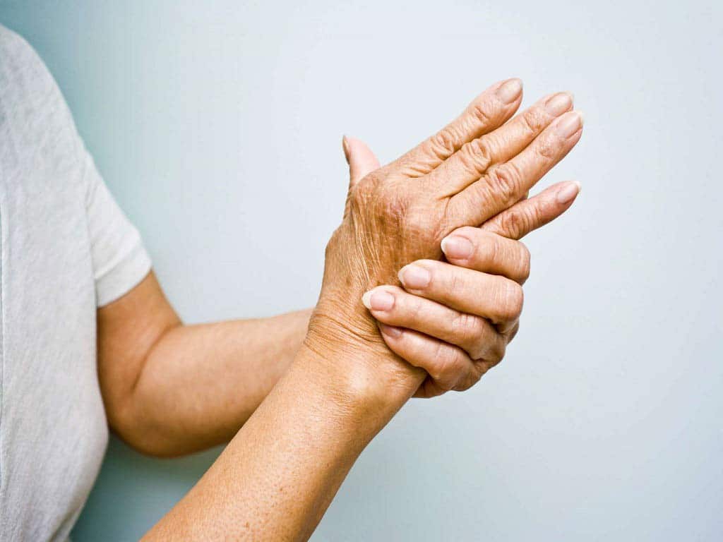 An elderly woman holding her wrist in pain.