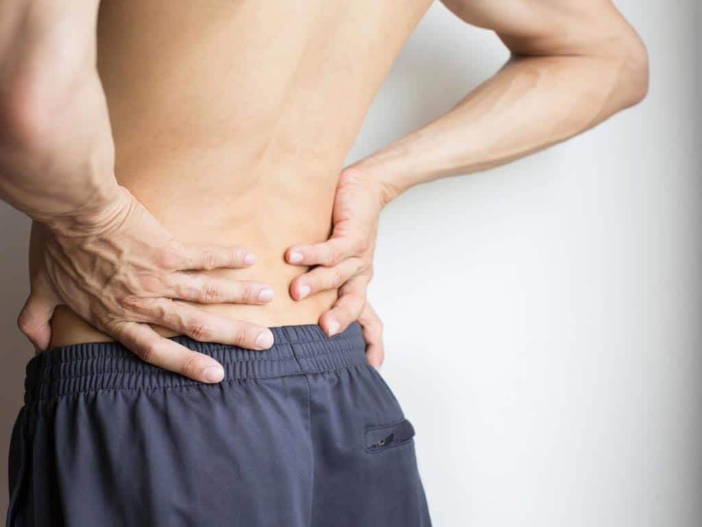 A man experiencing lower back pain because of a bulging disc