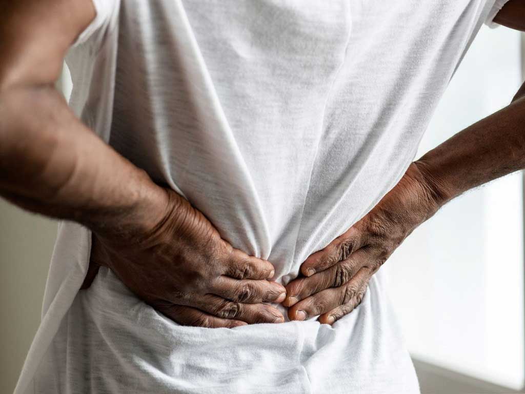 A person holding their lower back with both hands due to pain