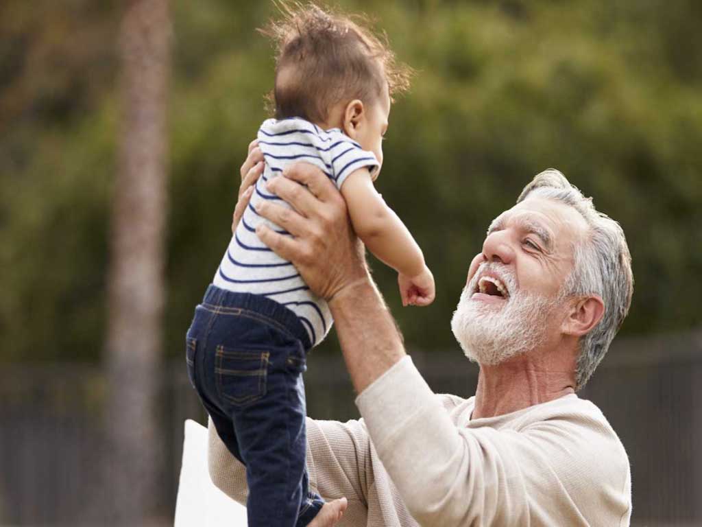 An elderly man lifting his grandson