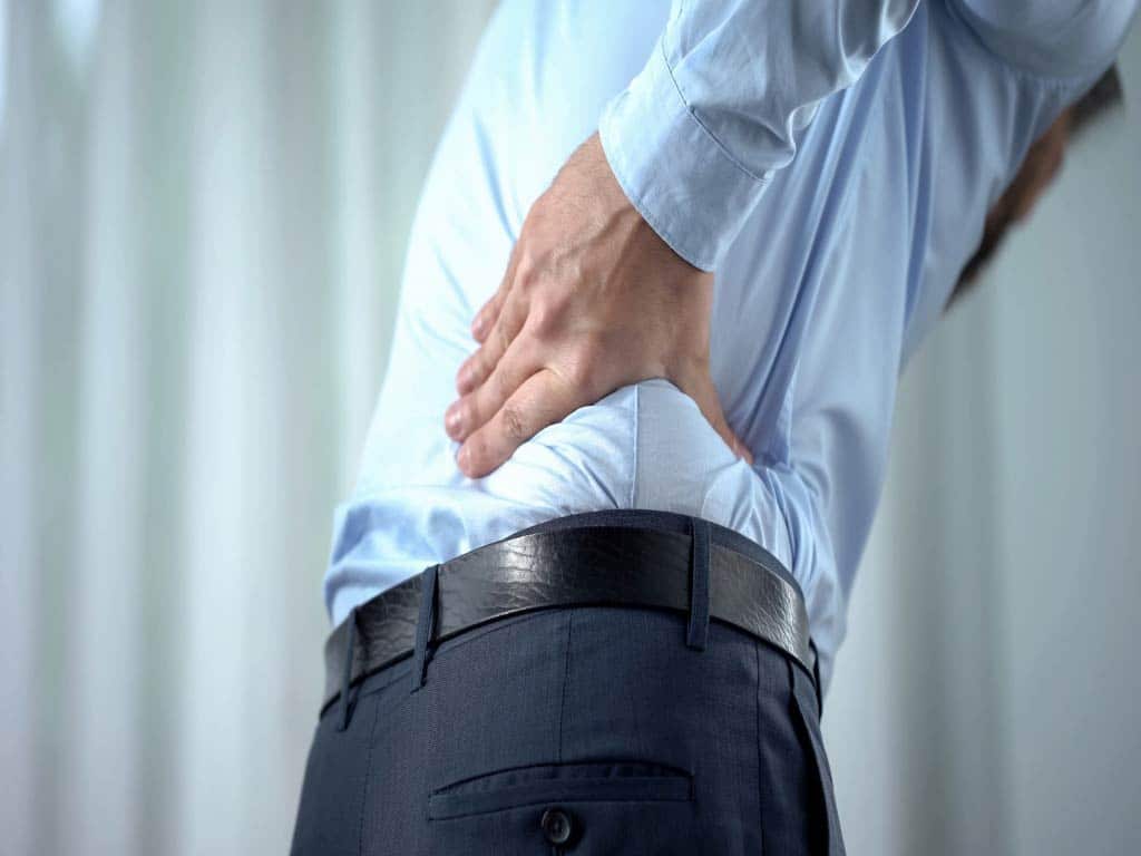 A male employee holding the right side of his lower back