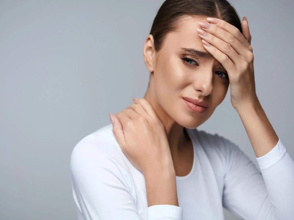 Woman holding her forehead and neck because of pain