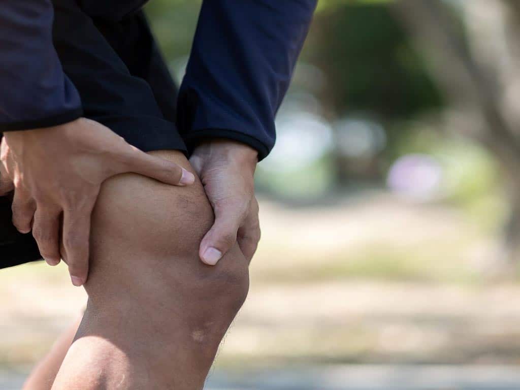 A person touching their knee with both hands