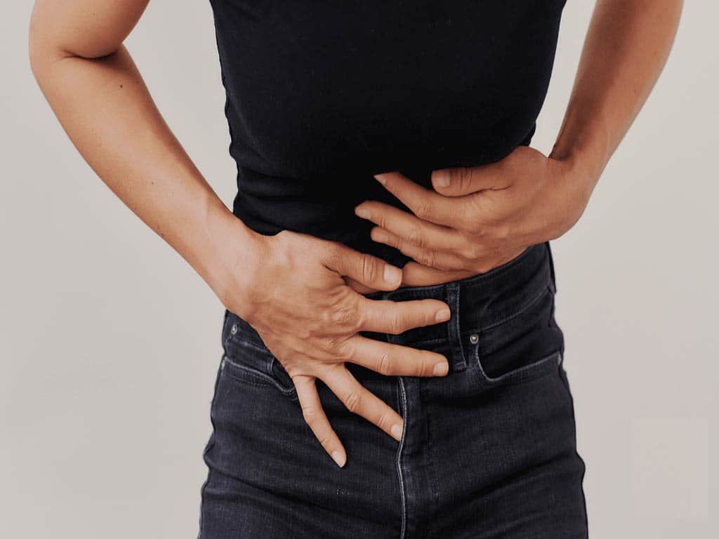 A woman holding her abdomen in discomfort