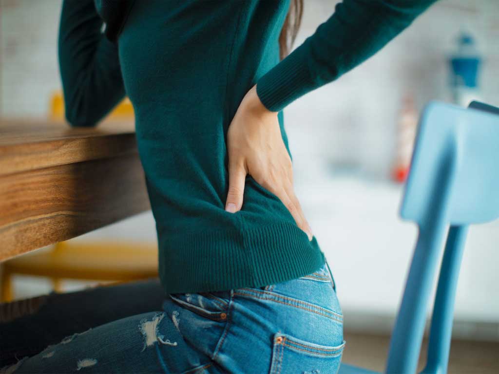 Woman holding the lower back while sitting
