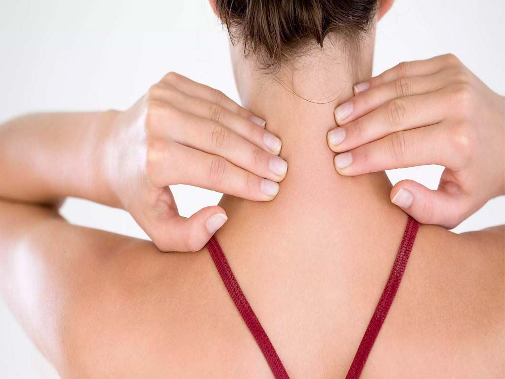 A woman touching the back of her neck with both hands