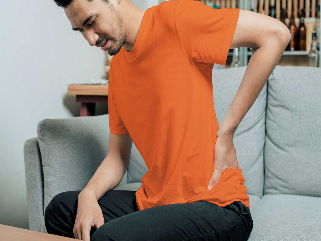 A man holding the side of his back while sitting