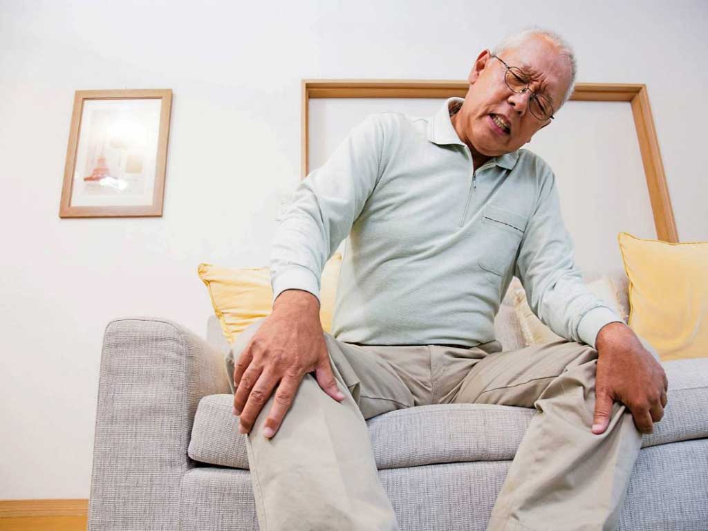 An elderly man clutching his pained knees