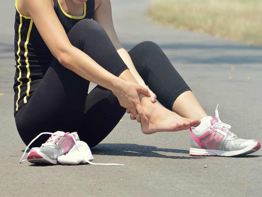 A woman touching her ankle due to pain after exercising