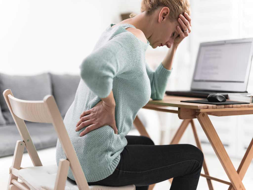 A woman touching her head and lower back due to pain