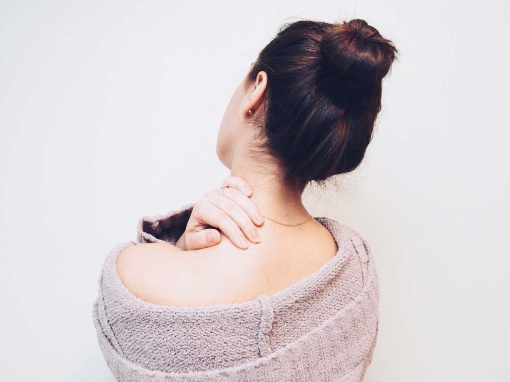 The back of a woman holding her shoulder