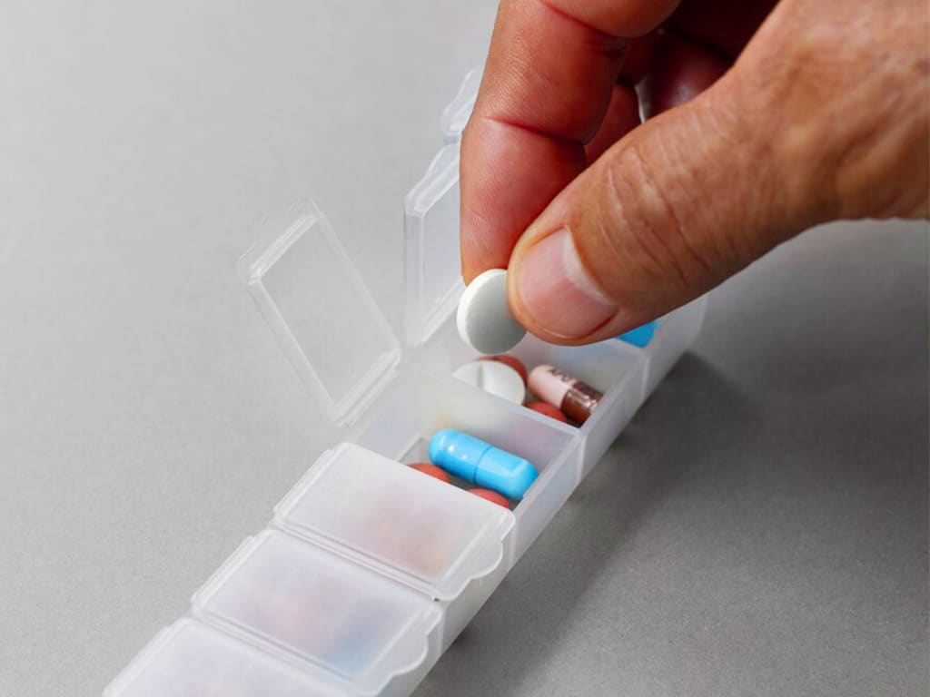 A person getting a Vitamin C tablet from their medicine container