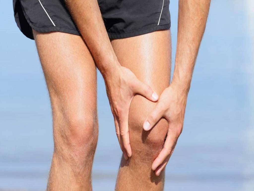 A person holding his knee with both hands due to arthritis pain