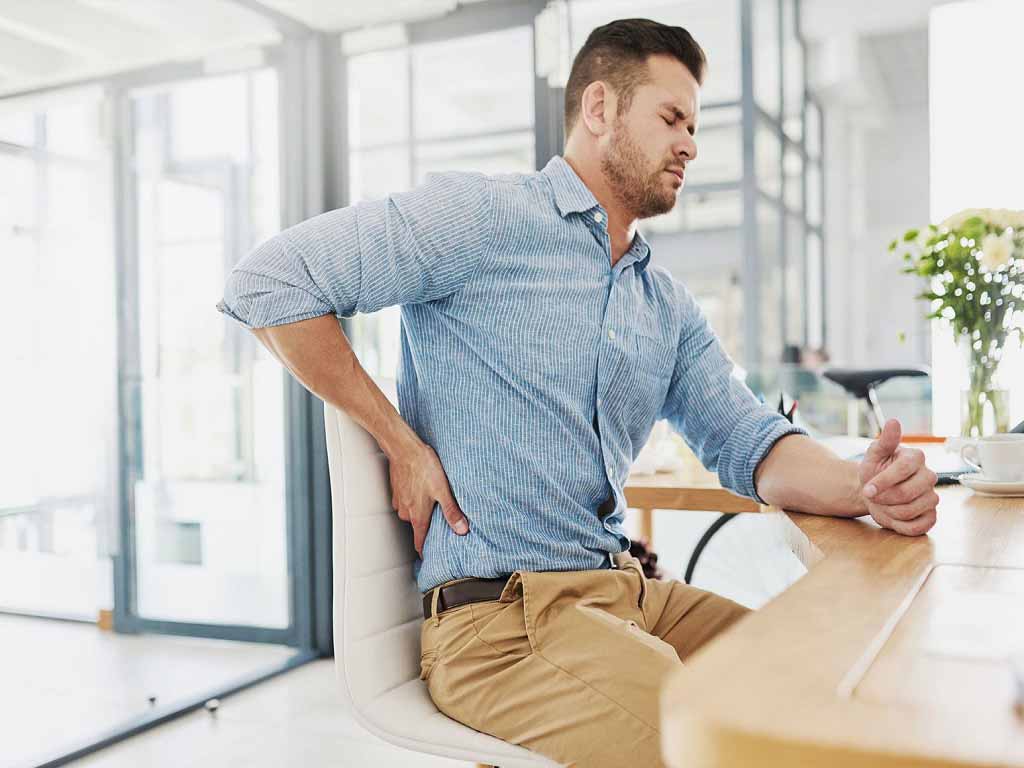 A man experiencing back pain while working