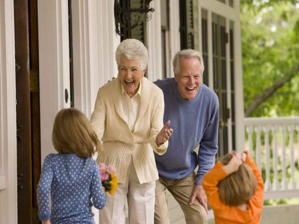 Two elderly people wearing smiles while interacting with a pair of youthful children