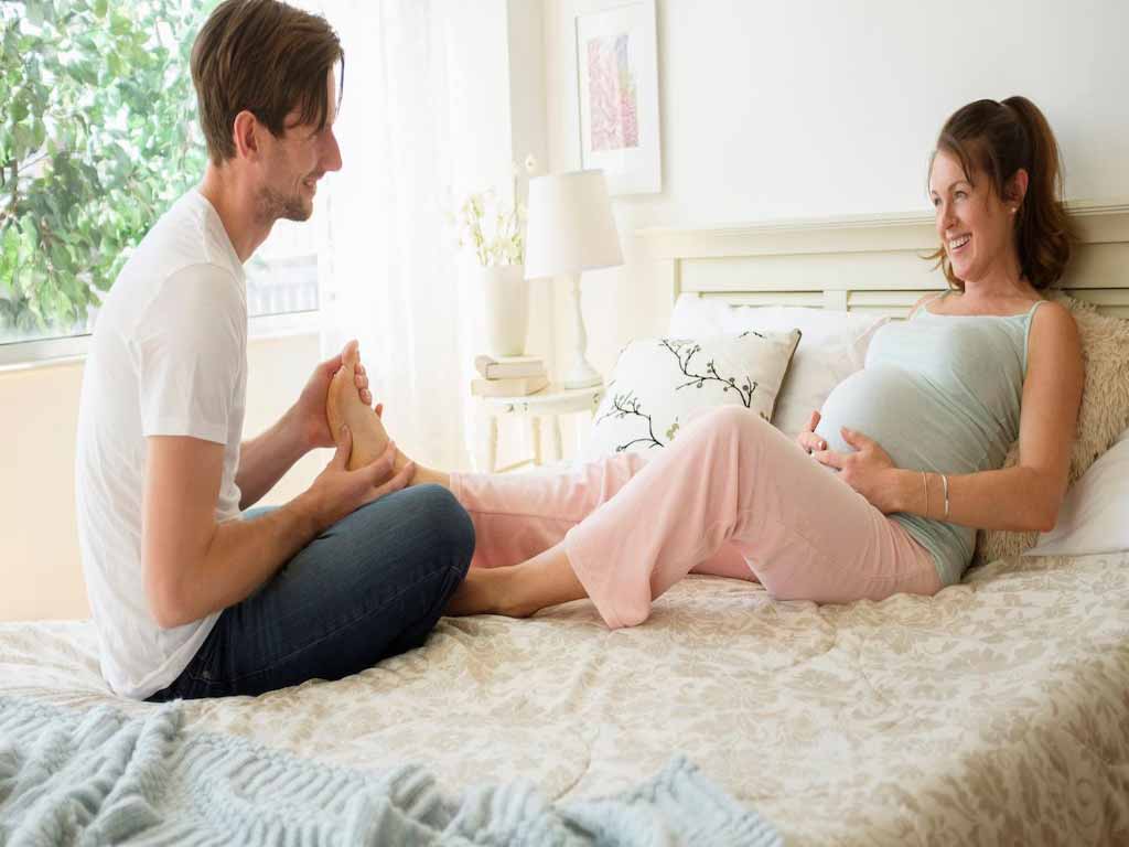 A husband massaging the feet of his pregnant wife
