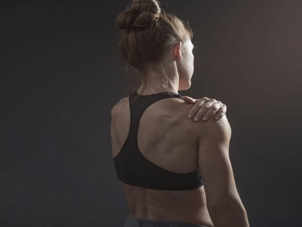 Woman holding her sore shoulder after a workout