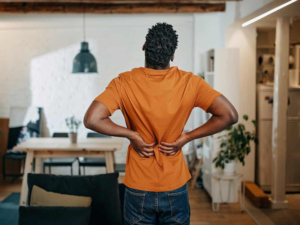 A man in the middle of a room experiencing severe back pain